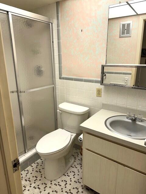 331 Tequesta Dr Unit 212, Tequesta, FL 33469 - full bath featuring vanity, a stall shower, toilet, and tile walls