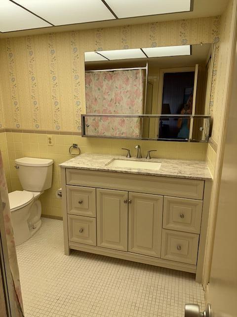 331 Tequesta Dr Unit 212, Tequesta, FL 33469 - bathroom featuring a wainscoted wall, vanity, toilet, wallpapered walls, and tile patterned floors