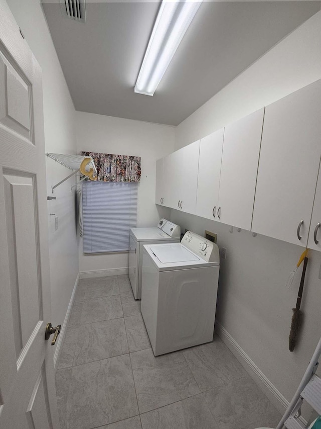 clothes washing area featuring light tile patterned floors, washing machine and clothes dryer, visible vents, baseboards, and cabinet space
