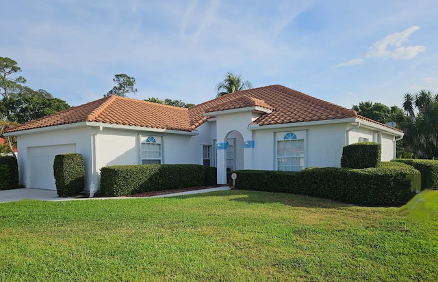 mediterranean / spanish-style home with stucco siding, a garage, a front lawn, and a tile roof