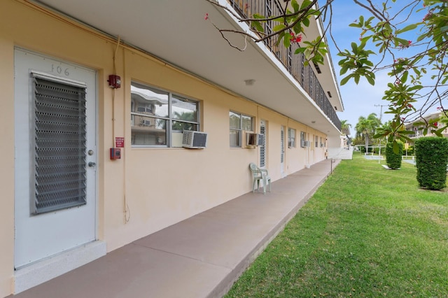 exterior space with stucco siding, a yard, and cooling unit