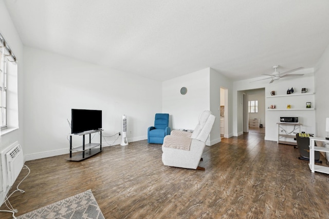 living area featuring baseboards, a ceiling fan, and wood finished floors