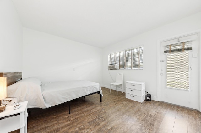 bedroom featuring baseboards, vaulted ceiling, wood finished floors, and cooling unit