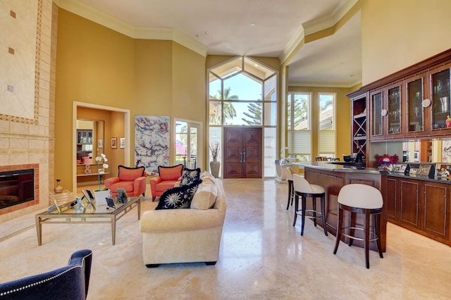 living room with crown molding, a large fireplace, and a high ceiling