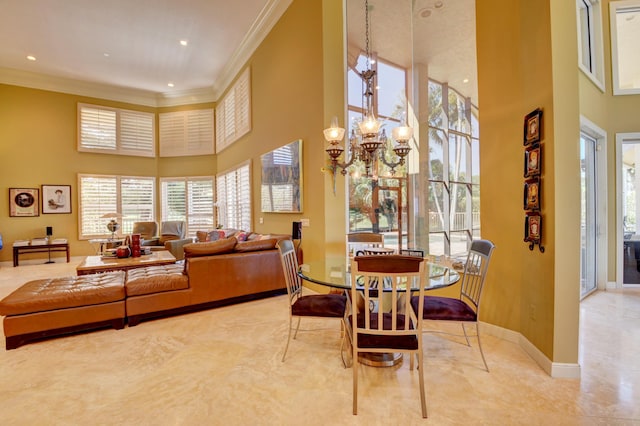 dining room with baseboards, ornamental molding, a towering ceiling, and a chandelier