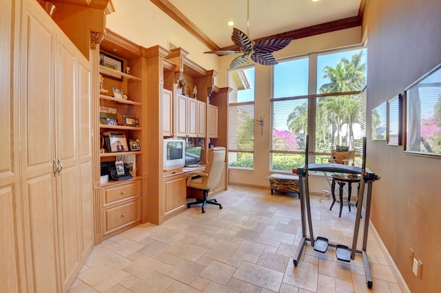 office space featuring ceiling fan, built in study area, baseboards, ornamental molding, and stone tile floors