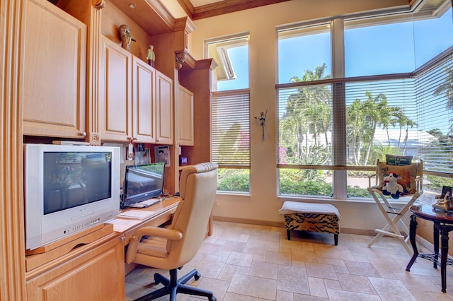 office space with baseboards, stone tile floors, built in desk, and ornamental molding