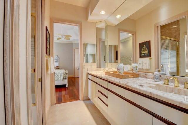 full bath featuring double vanity, a sink, connected bathroom, and a shower with door
