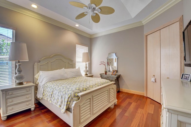 bedroom with recessed lighting, baseboards, wood finished floors, ornamental molding, and a closet