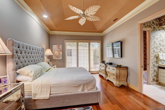 bedroom with a ceiling fan, visible vents, wood finished floors, ornamental molding, and a tray ceiling