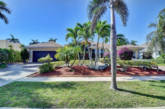 view of front of property with a garage, stucco siding, decorative driveway, and a front yard
