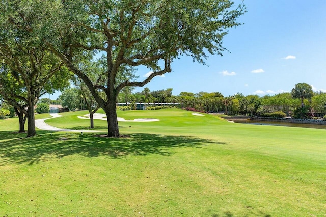 view of home's community with a lawn, a water view, and golf course view