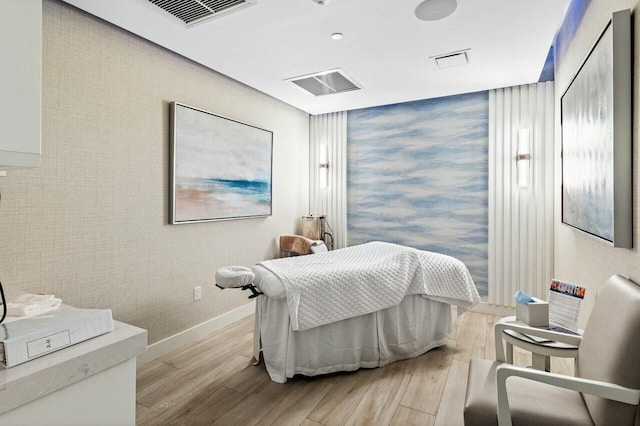 bedroom with baseboards, visible vents, and wood finished floors
