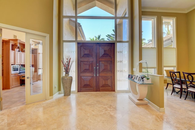 entrance foyer featuring crown molding, a high ceiling, and french doors