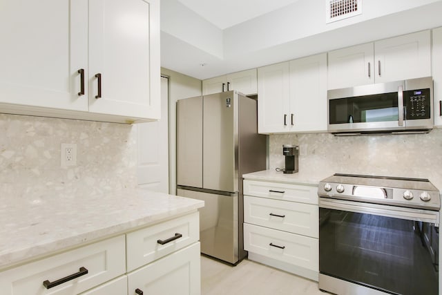 254 Village Blvd Unit 4207, Tequesta, FL 33469 - kitchen featuring appliances with stainless steel finishes, decorative backsplash, light stone counters, and light wood-style floors