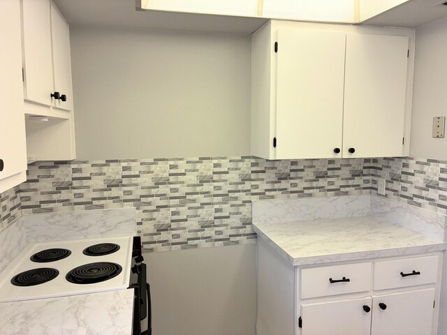 kitchen featuring backsplash, white cabinets, range with electric stovetop, and light countertops