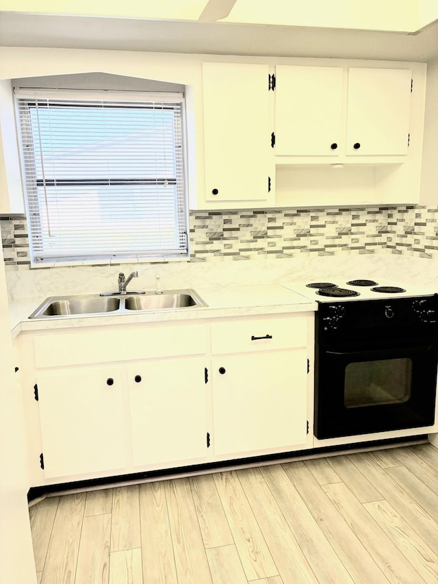 kitchen with light countertops, electric range, white cabinets, and a sink