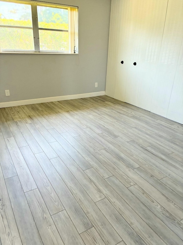 empty room featuring baseboards and light wood finished floors