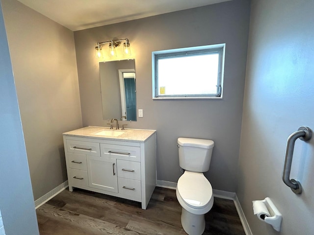 bathroom with toilet, baseboards, wood finished floors, and vanity