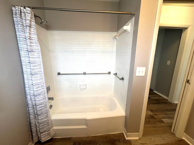full bath featuring baseboards, wood finished floors, and shower / bath combo
