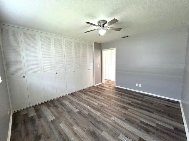 unfurnished bedroom with ceiling fan, visible vents, wood finished floors, baseboards, and a closet