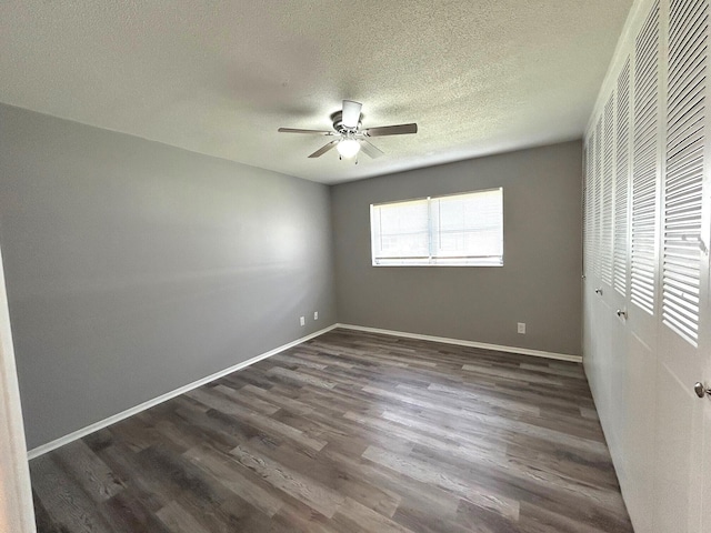 unfurnished bedroom with dark wood-style flooring, a textured ceiling, baseboards, and a closet