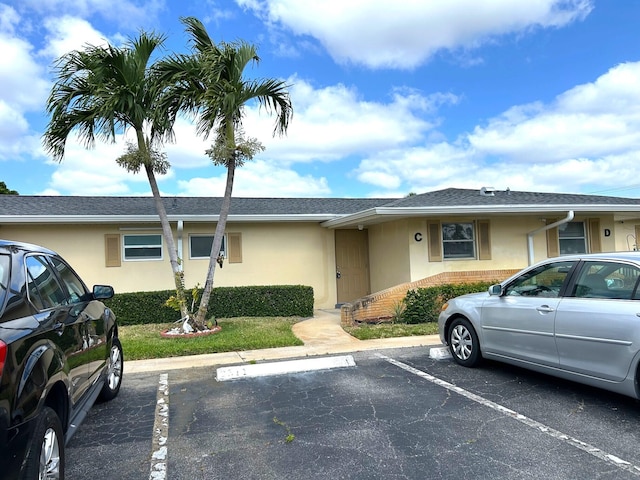 view of front facade with stucco siding and uncovered parking
