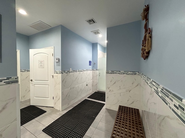 full bath featuring tile walls, a wainscoted wall, walk in shower, and visible vents