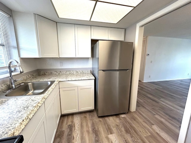 kitchen with freestanding refrigerator, light wood-style floors, range, a sink, and backsplash
