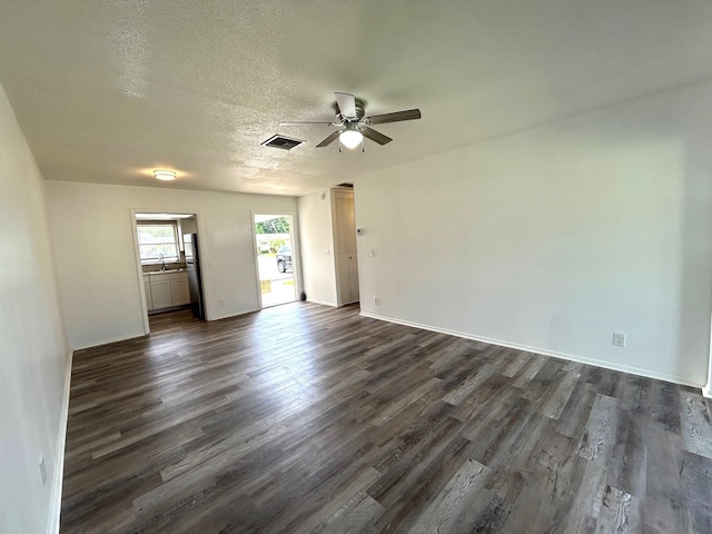 spare room with a sink, a ceiling fan, dark wood finished floors, and visible vents