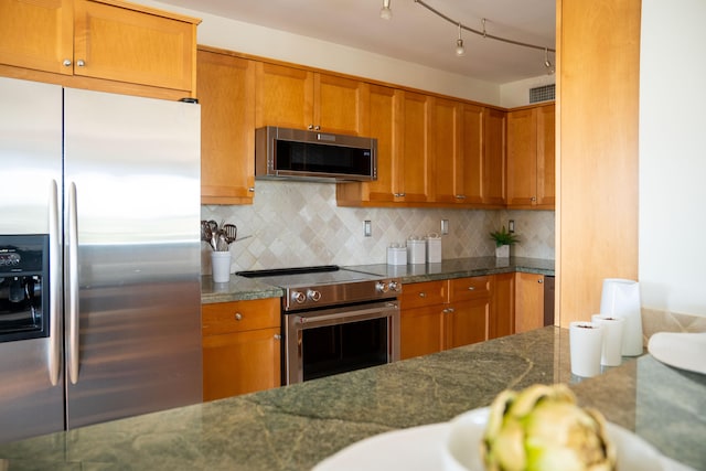 2500 E Las Olas Blvd Unit 802, Fort Lauderdale, FL 33301 - kitchen with stainless steel appliances, brown cabinetry, backsplash, and dark stone counters