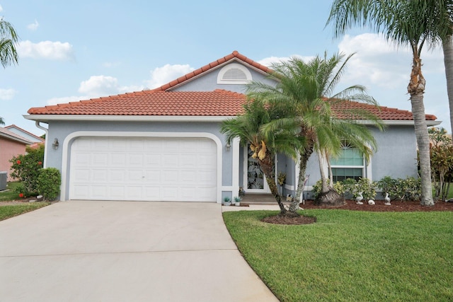 mediterranean / spanish-style home with a garage, a front yard, stucco siding, a tiled roof, and concrete driveway