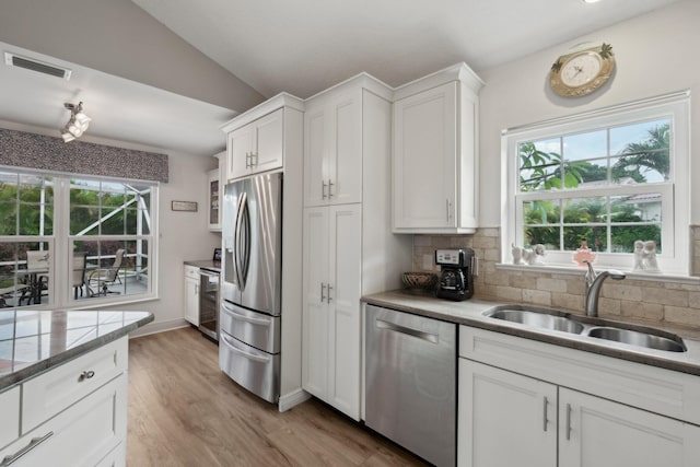 kitchen featuring plenty of natural light, visible vents, a sink, lofted ceiling, and stainless steel appliances