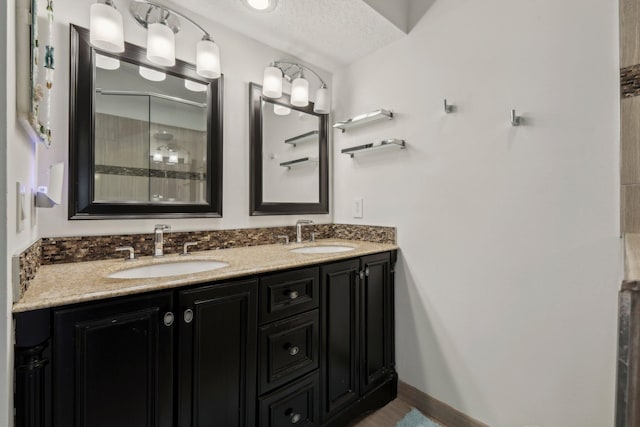 bathroom featuring double vanity, tiled shower, and a sink