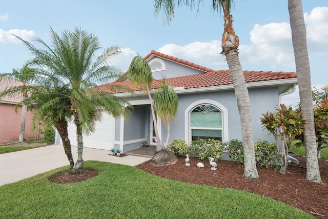 mediterranean / spanish house featuring a garage, a front yard, stucco siding, a tiled roof, and concrete driveway