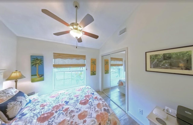 bedroom with a ceiling fan, visible vents, vaulted ceiling, wood finished floors, and a closet