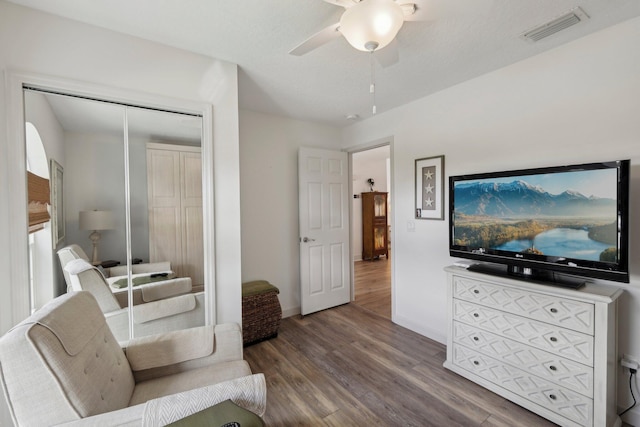 sitting room with baseboards, ceiling fan, visible vents, and wood finished floors
