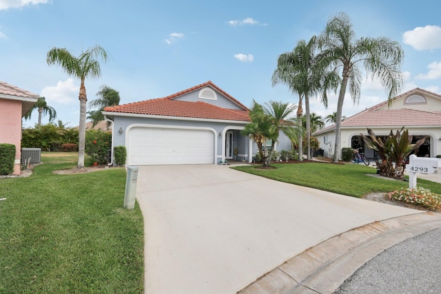 mediterranean / spanish home featuring driveway, a tile roof, a front yard, a garage, and stucco siding