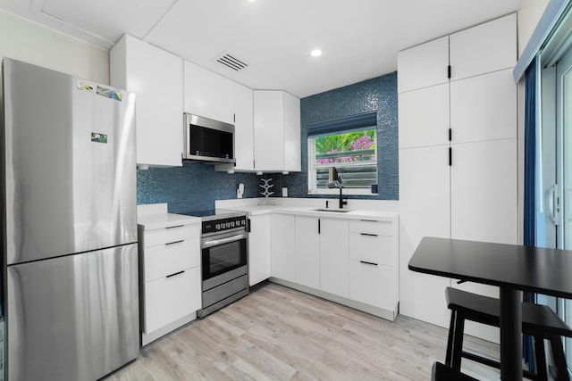 425 32nd St, West Palm Beach, FL 33407 - kitchen featuring stainless steel appliances, light countertops, white cabinets, a sink, and recessed lighting