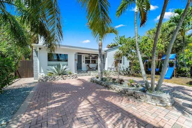 425 32nd St, West Palm Beach, FL 33407 - single story home with covered porch, stucco siding, a playground, and fence