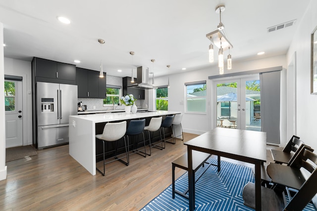 425 32nd St, West Palm Beach, FL 33407 - kitchen with high quality fridge, light countertops, dark cabinetry, island exhaust hood, and tasteful backsplash