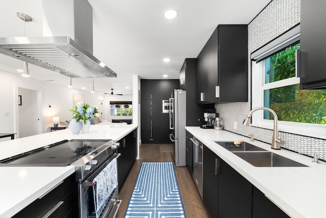 425 32nd St, West Palm Beach, FL 33407 - kitchen featuring dark cabinetry, stainless steel appliances, wall chimney exhaust hood, a sink, and light countertops