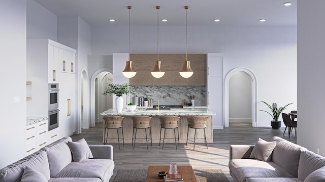 living area with recessed lighting, arched walkways, a high ceiling, and wood finished floors