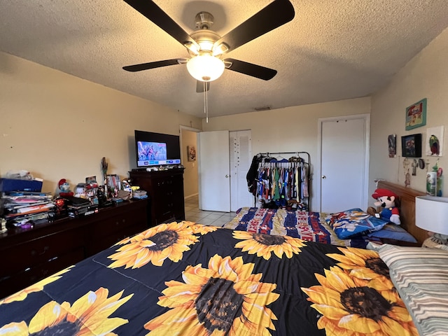 tiled bedroom featuring a textured ceiling, visible vents, ceiling fan, and a closet