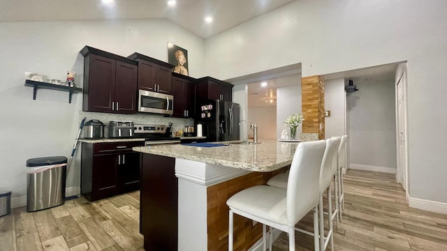 1044 Nin St, Orlando, FL 32835 - kitchen featuring stainless steel appliances, a breakfast bar area, backsplash, light wood-style floors, and high vaulted ceiling
