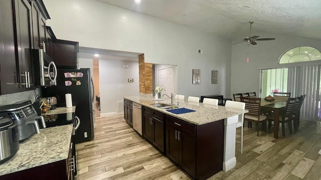 1044 Nin St, Orlando, FL 32835 - kitchen with appliances with stainless steel finishes, ceiling fan, a breakfast bar, high vaulted ceiling, and light wood finished floors