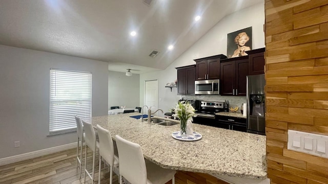 1044 Nin St, Orlando, FL 32835 - kitchen with stainless steel appliances, a breakfast bar, a kitchen island with sink, backsplash, and light wood finished floors