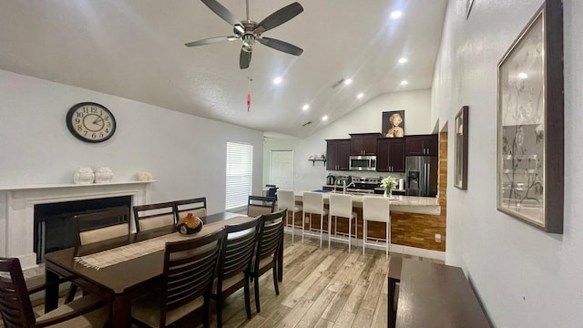 1044 Nin St, Orlando, FL 32835 - dining space with light wood-type flooring, a ceiling fan, vaulted ceiling, a fireplace, and baseboards