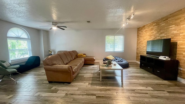 1044 Nin St, Orlando, FL 32835 - living room featuring a textured ceiling, light wood-style flooring, a ceiling fan, rail lighting, and baseboards