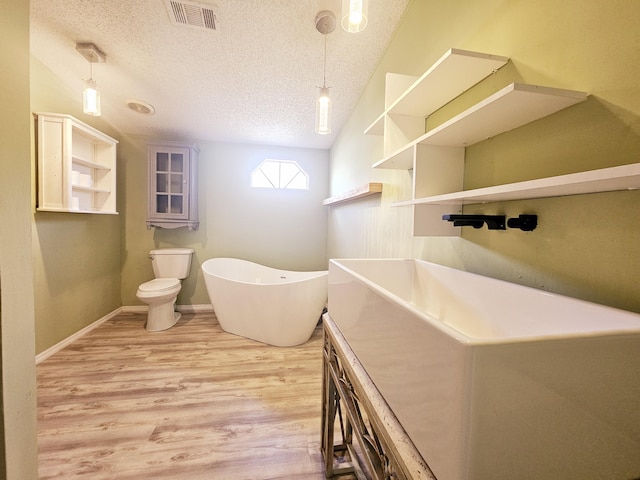 17120 NW 38th Ave, Okeechobee, FL 34972 - full bath with wood finished floors, toilet, visible vents, a textured ceiling, and a soaking tub